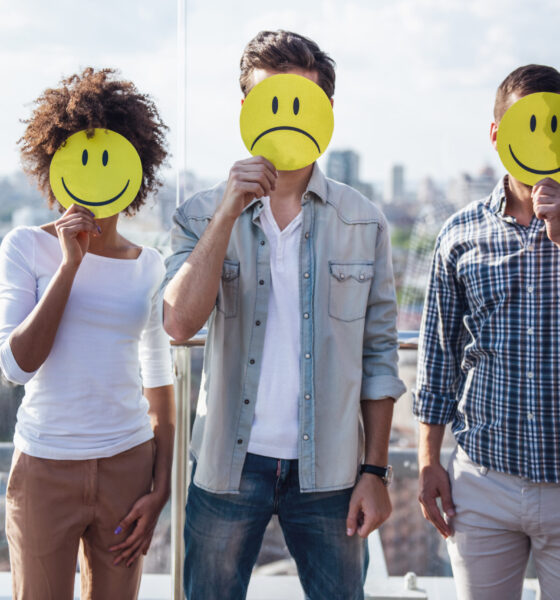 Young people holding emojis while standing on balcony of the city building